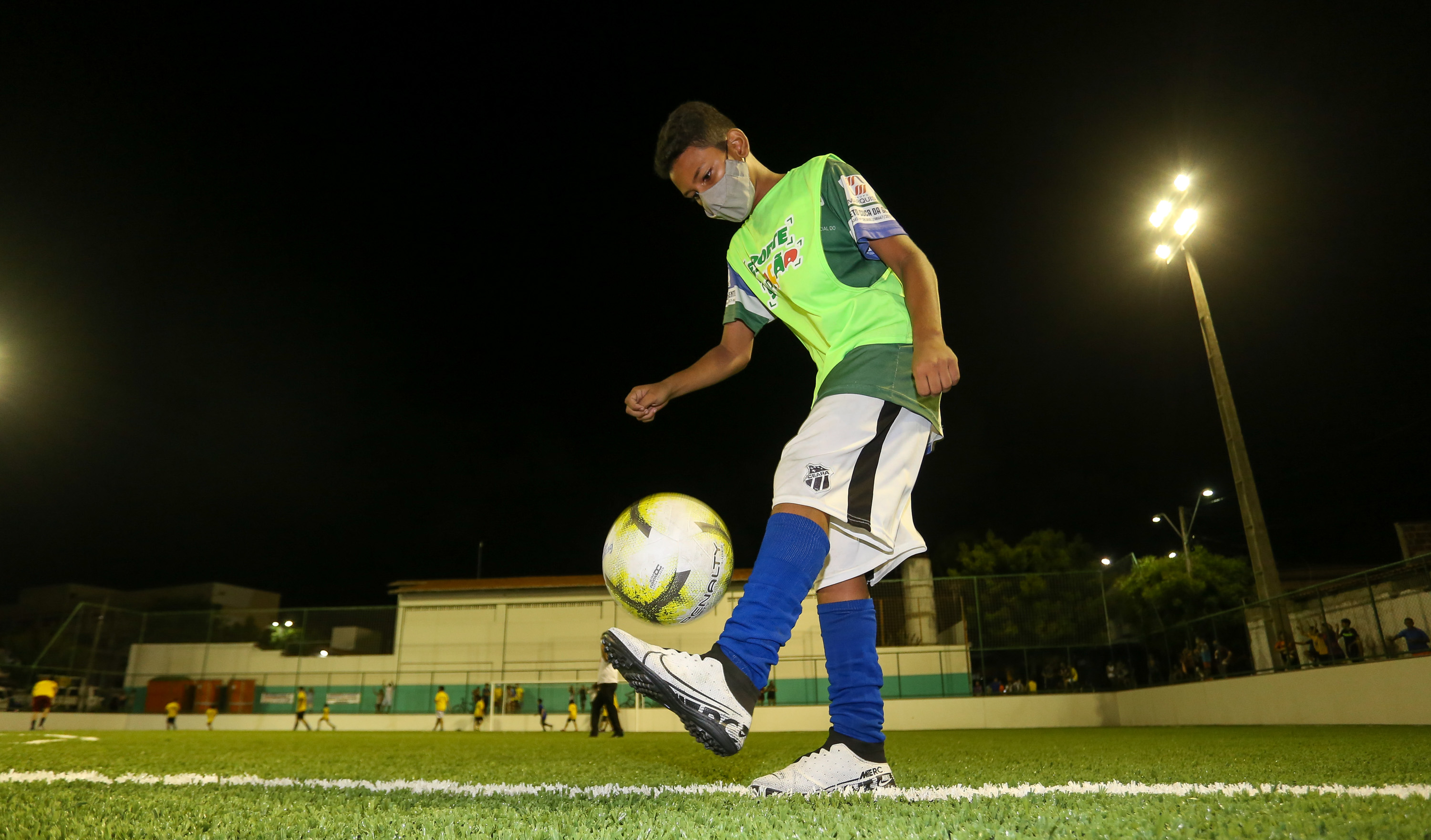 menino faz embaixadinha com uma bola de futebol